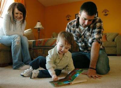 Nicole and Justin Hertel read with their 15-month-old son Damien, on Saturday, Jan. 31, 2009 in their Hebron, Ky. home. <br/>(Photo: AP Images / The Enquirer, Carrie Cochran)