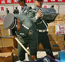 Beijing Cultural Law Enforcement Agency officers destroy pirated DVDs and CDs video and music material in the outskirts of Beijing, China Saturday April 14, 2007. China has promised to pursue product pirates identified by American authorities in a new effort to stamp out its thriving counterfeit industry, the head of the U.S. customs agency said Friday June 15, 2007. <br/>