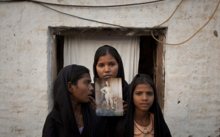 Asia Bibi's daughters pose with a photograph of their mother. <br/>CNS