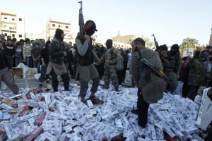 Isis militants stand on a pile of confiscated cigarette cartons, before setting fire to them. <br/>Reuters