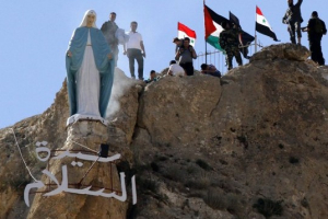 Members of the Syrian National Defense Forces (NDF) stand behind a statue of Virgin Mary perched on the cliffs overlooking the ancient Christian town of Maalula on June 13, 2015 after the statue was restored to its original place.  <br/>AFP Photo/ Louai Beshara