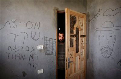 A Palestinian man looks through a door as he stands in a home commandeered by Israeli soldiers during the recent Gaza offensive, in Gaza City, Monday, March 23, 2009. The Hebrew graffiti on the wall reads 'The eternal people has no fear', bottom, and 'Shaked', a name referring to an army battalion. In recent testimony, several Israeli soldiers confirmed they were engaged in unnecessary destruction. <br/>(Photo: AP / Hatem Moussa)