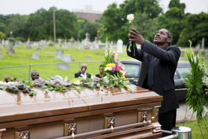 Gary Washington holds up a rose before placing it on the casket of his mother, Ethel Lance, following her burial service, June 25, 2015, in Charleston, S.C. <br/>AP Photo