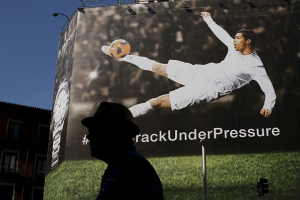 A man walks past a billboard displaying an image of Real Madrid's soccer player Cristiano Ronaldo kicking a ball as part of an advertising campaign in central Madrid, Spain, June 25, 2015. REUTERS/Susana Vera <br/>