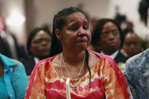 Esaw Garner (C), widow of Eric Garner, sheds a tear while holding a candle during the Interfaith Prayer Service for Healing and Reconciliation at the Mount Sinai United Christian Church in the Staten Island borough of New York July 14, 2015. One day after settling a $5.9 million wrongful death case with New York City, the family of Eric Garner renewed calls to criminally charge the police officer who put him in a fatal chokehold last July. REUTERS/Shannon Stapleton <br/>