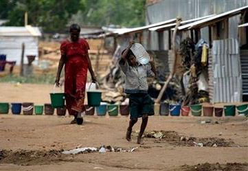 In this photo taken on Tuesday, May 26, 2009, a young Tamil boy carries a bottle of water in front of an old woman carrying buckets at a water collecting area at the Manik Farm refugee camp located on the outskirts of the northern Sri Lankan town of Vavuniya. <br/>(Photo: AP / David Gray, Pool)