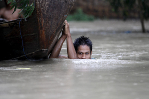 A boy moves his boat in a flooded village outside Zalun Township, Irrawaddy Delta, Myanmar, August 6, 2015. Myanmar's president urged people to leave the low-lying southern delta region on Thursday with rain water that has inundated much of the country flowing into the area threatening further flooding as rivers reached dangerously high levels. REUTERS/Soe Zeya Tun <br/>