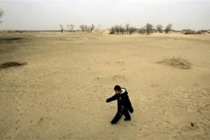 A child walks on the sand dune in Waixi, Gansu province, China, March 17, 2007. In a problem that's pervasive in much of China, overfarming has drawn down the water table so low that desert is overtaking farmland. Authorities have ordered farmers in Gansu province to vacate their properties over the next 3 years, and will replace 20 villages with newly planted grass in a final effort to halt the advance of the Tengger and Badain Jaran deserts. <br/>