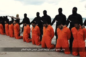 Men in orange jumpsuits purported to be Egyptian Christians held captive by the Islamic State (IS) kneel in front of armed men along a beach said to be near Tripoli in February 2015. <br/>Reuters