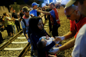 A migrant holds a child as they try to enter a train at a train station in Tovarnik, September 19, 2015. REUTERS/Antonio Bronic <br/>