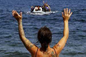 A volunteer signals at a dinghy with Afghan migrants at a beach on the Greek island of Lesbos, after the dinghy crossed a part of the Aegean Sea from the Turkish coast September 21, 2015. REUTERS/Yannis Behrakis <br/>