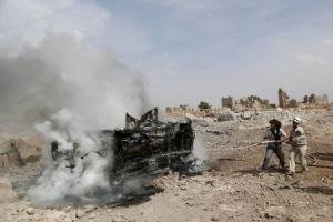 Civil defense members put out the flames on a burning military vehicle at a base controlled by rebel fighters from the Ahrar al-Sham Movement, that was targeted by what activists said were Russian airstrikes at Hass ancient cemeteries in the southern countryside of Idlib, Syria October 1, 2015.  <br/>REUTERS/Khalil Ashawi