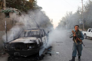 An Afghan policeman patrols next to a burning vehicle in Kunduz, Afghanistan . <br/>Reuters