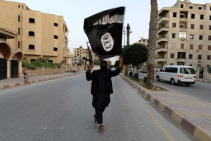 A member loyal to the Islamic State in Iraq and the Levant (ISIL) waves an ISIL flag in Raqqa June 29, 2014.  <br/>Reuters/Stringer