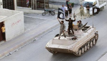 Militant Islamist fighters hold the flag of Islamic State (IS) while taking part in a military parade along the streets of northern Raqqa province in this June 30, 2014 file photo.  <br/>REUTERS/Stringer