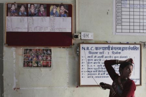 A woman stands next to a board displaying before-and-after treatment pictures of severely malnourished children at the Nutritional Rehabilitation Centre of Shivpuri district in Madhya Pradesh February 1, 2012. <br/> REUTERS/Adnan Abidi/Files