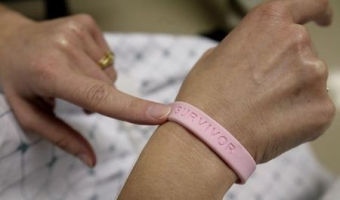 After three operations and four rounds of chemotherapy at Georgetown University Hospital, cancer patient Deborah Charles shows off her breast cancer survivor bracelet during a hospital appointment in Washington May 23, 2007. <br/> REUTERS/Jim Bourg