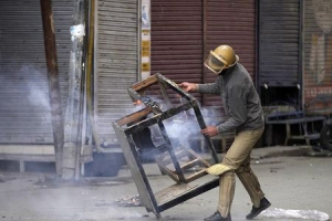 An Indian policeman removes a damaged table after it was set on fire by the supporters of Jammu Kashmir Liberation Front (JKLF), a Kashmiri separatist party, during a protest in Srinagar October 20, 2015 against the detention of its chief, Mohammad Yasin Malik. <br/> REUTERS/Danish Ismail