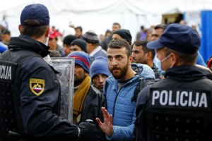 A migrant talks to Slovenian police officers at the exit of a makeshift camp near the Austrian border in Sentilj, Slovenia, October 20, 2015.  <br/>REUTERS/Leonhard Foeger