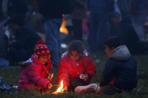 Migrants' children keep themselves warm around a fire after crossing the border from Croatia in Rigonce, Slovenia, October 22, 2015. <br/> REUTERS/Srdjan Zivulovic