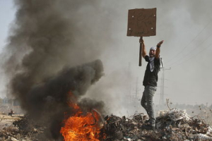 A Palestinian protester holding a sign shouts during clashes with Israeli troops near the border with Israel, in the east of Gaza City, in this October 16, 2015 file photo.  <br/>REUTERS/Mohammed Salem