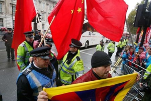 A Pro-Tibet protester is escorted by a police officer as supporters of China's President Xi Jinping wave Chinese flags next to him outside Downing Street in central London, Britain, October 21, 2015.  <br/>REUTERS/Peter Nicholls