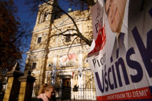 An election poster of Law and Justice's (PiS) candidate Piotr Uscinski is seen in front of a church in Radzymin near Warsaw, Poland October 27, 2015. Church attendance may be falling in Poland as elsewhere across Europe, but the victory of conservative opposition Law and Justice party in Sunday's election will likely advance the role of Roman Catholic values in public life and government.  <br/>REUTERS/Kacper Pempel