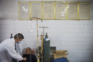 Fu Jianghua (L), the head of Yangjia Hospital, checks a patient in the hospital in Wuyi County, Zhejiang Province, China October 19, 2015 <br/>Reuters