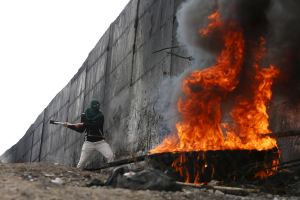 A Palestinian protester tries to hammer a hole through the Israeli barrier that separates the West Bank town of Abu Dis from Jerusalem, during clashes with Israeli troops October 28, 2015.  <br/>REUTERS/Ammar Awad