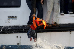 A refugee prepares to hand over a toddler to a volunteer lifeguard as a half-sunken catamaran carrying around 150 refugees, most of them Syrians, arrives after crossing part of the Aegean sea from Turkey on the Greek island of Lesbos, October 30, 2015. <br/> REUTERS/Giorgos Moutafis