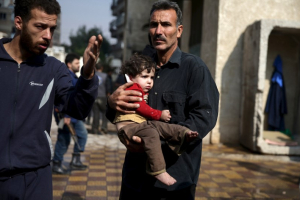 A man carries an injured child as another man gestures at a site hit by missiles fired by Syrian government forces on a busy marketplace in the Douma neighborhood of Damascus, Syria October 30, 2015. <br/> REUTERS/Bassam Khabieh