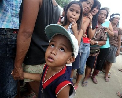 In this photo taken Wednesday, Oct. 14, 2009, displaced residents queue up for food and relief supplies at a distribution center in Rosales township, Pangasinan province in northern Philippines. The Philippines will be seeking at least $1 billion from international donors for reconstruction after devastating back-to-back storms highlighted the country's vulnerability to climate change, officials said Wednesday. <br/>AP Images / Bullit Marquez