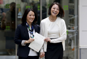 Hiroko Masuhara (L) and her partner Koyuki Higashi hold their partnership certificate as they walk out from the Shibuya ward office after the ward office issued the nation's first same sex partnership certificates in Tokyo, Japan, November 5, 2015.  <br/>Reuters