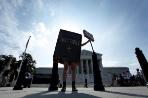 A protester dressed as a copy of the Bible joins groups demonstrating outside the U.S. Supreme Court in Washington June 30, 2014. <br/>Reuters