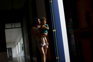 Eliene Almeida, head teacher at the municipal school in Bento Rodrigues district, witch was covered with mud after a dam, owned by Vale SA and BHP Billiton Ltd burst, carries her kid at a hotel housing the people displaced from the village, in Mariana, Brazil, November 9, 2015. <br/>Reuters