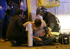 French fire brigade members aid an injured individual near the Bataclan concert hall following fatal shootings in Paris, November 13, 2015. REUTERS/Christian Hartmann <br/>