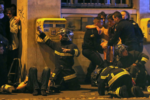 French fire brigade members aid an injured individual near the Bataclan concert hall following fatal shootings in Paris, November 13, 2015. REUTERS/Christian Hartmann <br/>