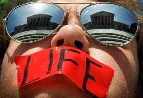 Anti-abortion activist Craig Kuhns wears mirrored sunglasses and a piece of tape over his mouth as he stands in front of the US Supreme Court building in Washington, in this June 1, 2009 file photo. <br/>Reuters