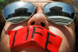 Anti-abortion activist Craig Kuhns wears mirrored sunglasses and a piece of tape over his mouth as he stands in front of the US Supreme Court building in Washington, in this June 1, 2009 file photo. <br/>Reuters