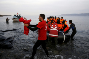 A Red Cross volunteer carries a Syrian refugee baby off an overcrowded raft at a beach on the Greek island of Lesbos November 16, 2015. <br/>Reuters
