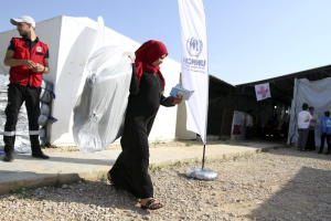 A Syrian refugee carries a bag she received as aid for the winter from the United Nations refugee agency (UNHCR) in Tripoli, northern Lebanon November 18, 2015. <br/>Reuters