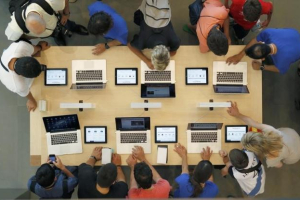 Employees and customers surround a table with MacBook Pros, during the official opening of the largest Apple shop in southern Europe, at Passeig de Gracia in Barcelona July 28, 2012. (Reuters/Albert Gea/Files) <br/>