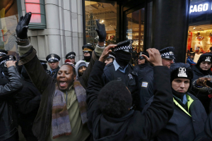 Demonstators hold their hands up in front of Chicago Police officers during protest of last year's shooting death of black teenager Laquan McDonald by a white policeman and the city's handling of the case in the downtown shopping district of Chicago, Illinois, November 27, 2015.  <br/>Reuters