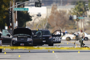 A police officer picks up a weapon from the scene of the investigation around the area of the SUV vehicle where two suspects were shot by police following a mass shooting in San Bernardino, California December 3, 2015.  <br/>Reuters