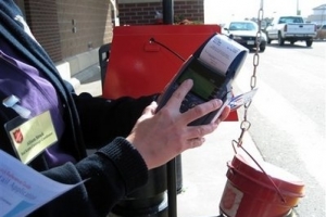 Salvation Army Red Kettle campaign manager Allison Struck shows a volunteer bell ringer how to use the charity's new plastic card readers at a station outside a Colorado Springs, Col., grocery store on Monday, Nov. 23, 2009. Colorado Springs is one of 30 cities where Salvation Army kettle collections will include an option for people who don't carry cash but want to donate using a credit or debit card. <br/>AP Images / Kristen Wyatt