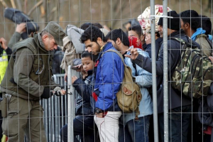 An Austrian soldier fixes the fence as migrants wait to cross the border into Spielfeld in Austria from the village of Sentilj, Slovenia, October 31, 2015.  <br/>Reuters