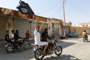 A resident of Tabqa city touring the streets on a motorcycle waves an Islamist flag in celebration after Islamic State militants took over Tabqa air base, in nearby Raqqa city, Syria, August 24, 2014.  <br/>Reuters