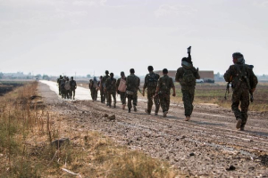 Kurdish fighters walk carrying their weapons towards Tel Abyad of Raqqa governorate after they said they took control of the area June 15, 2015.  <br/>Reuters