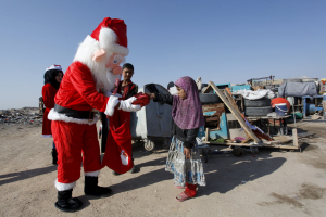 A volunteer wearing a Santa Claus costume distributes presents to children at a poor community in Najaf, south of Baghdad, December 19, 2015.  <br/>REUTERS/Alaa Al-Marjani