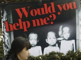 A South Korean woman walks past a picture of North Korean children allegedly suffering from famine during a rally denouncing North Korean leader Kim Jong Il's dictatorship and alleged human rights violations against North Koreans, in Seoul, South Korea, Wednesday, Dec. 30, 2009. <br/>AP Photo/ Lee Jin-man